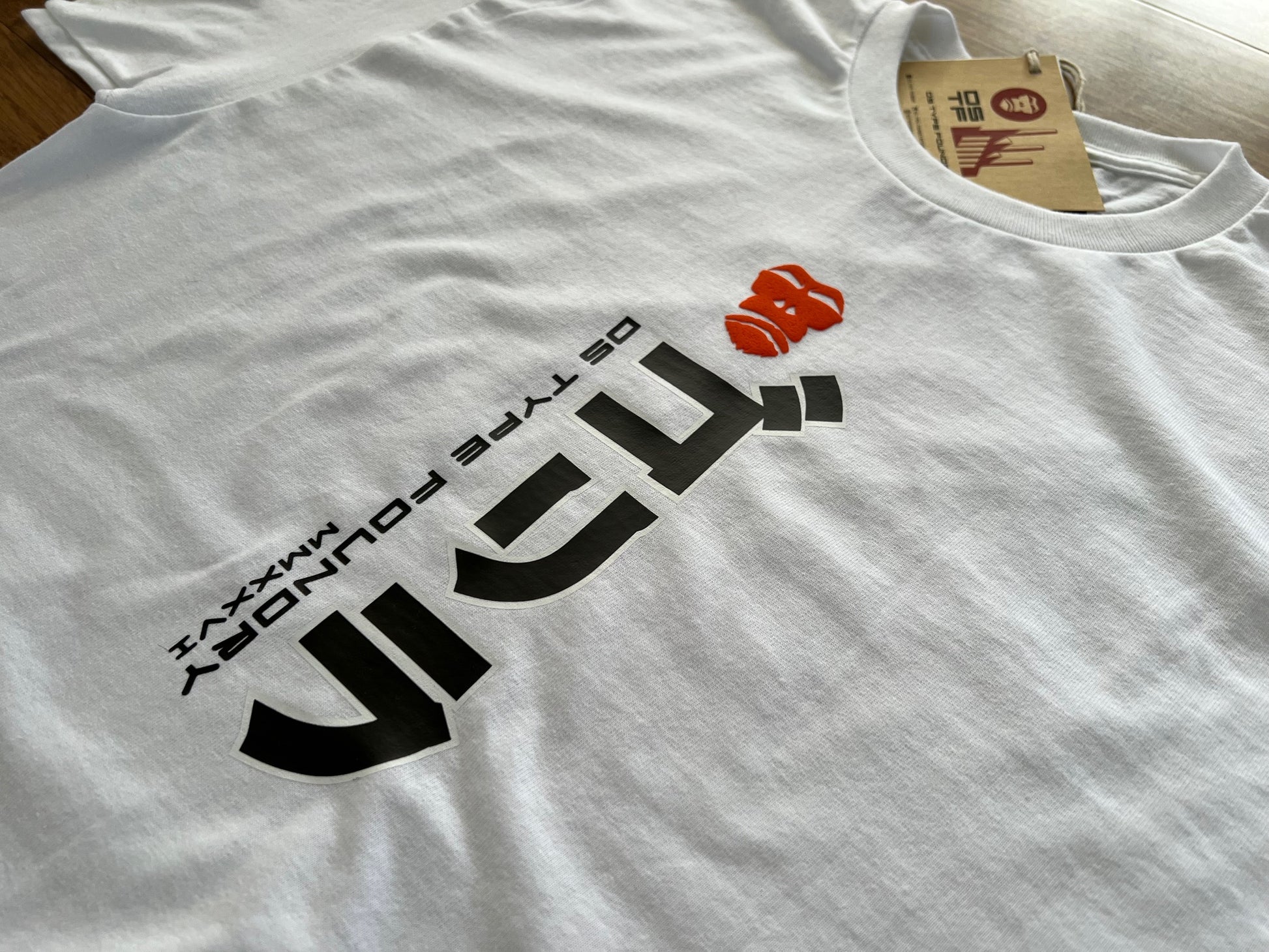 A white crewneck t-shirt featuring a bold black graphic print of the word 'Gorilla' in Japanese stylized lettering, with 'DS TYPE FOUNDRY' printed above it and a small red logo accent in puff raised ink. A paper brand tag is visible inside the collar.
