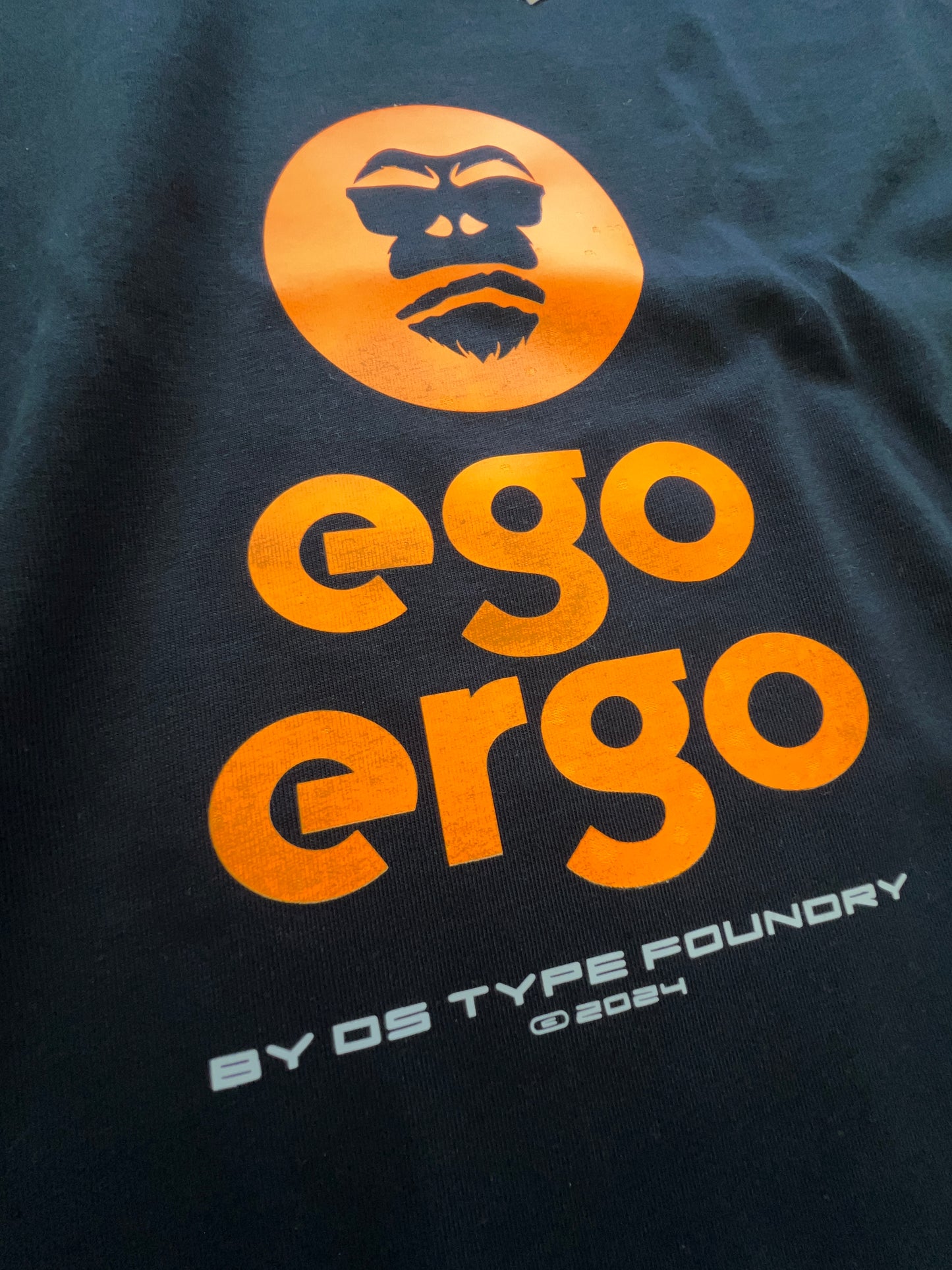 Ego Ergo in Neon Orange on dark navy blue tee, 100% cotton 220gsm. Typeface: Ego