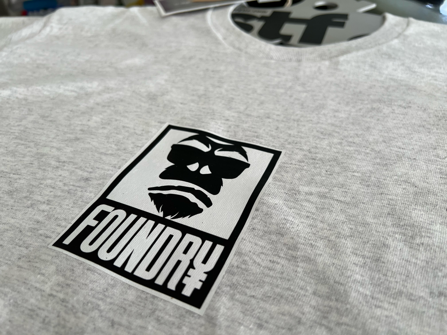 Gray t-shirt with a black white logo featuring gorilla and foundry typeface