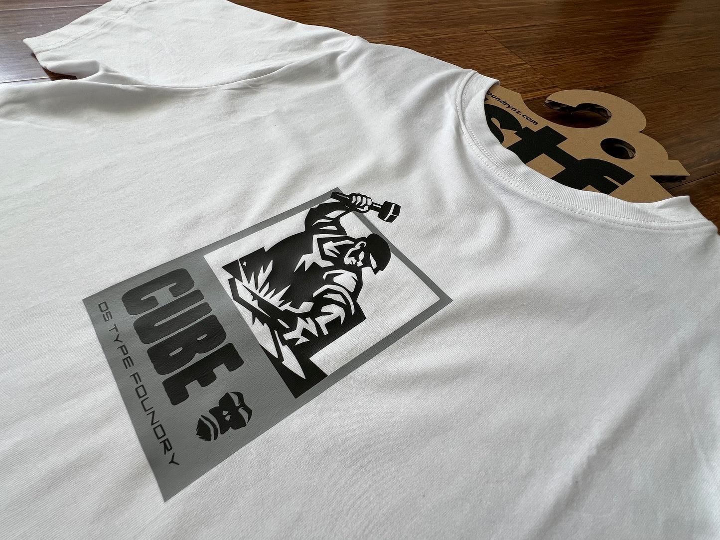 White t-shirt with black graphic design on a wooden surface