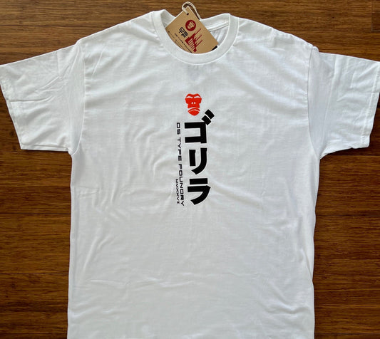 A white short-sleeve t-shirt laid flat on a brown wooden floor, featuring a black and red graphic print on the chest with lettering and 'DS TYPE FOUNDRY 