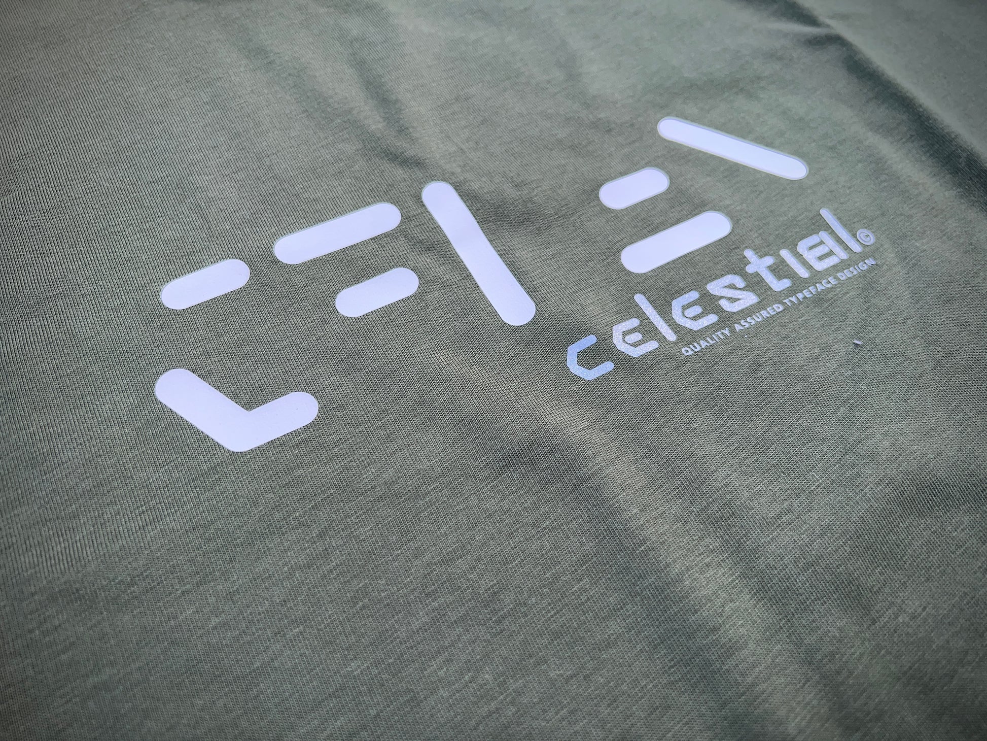 Celestial white and grey on khaki green tee. 100% cotton. Typeface: Celestial