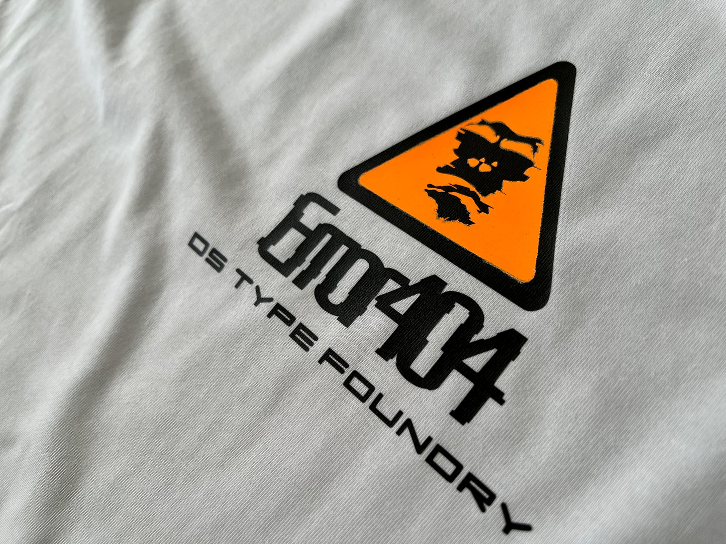 Close-up of a white fabric surface printed with a black and orange warning-style logo and the text 'END404' and 'DS TYPE FOUNDRY'.